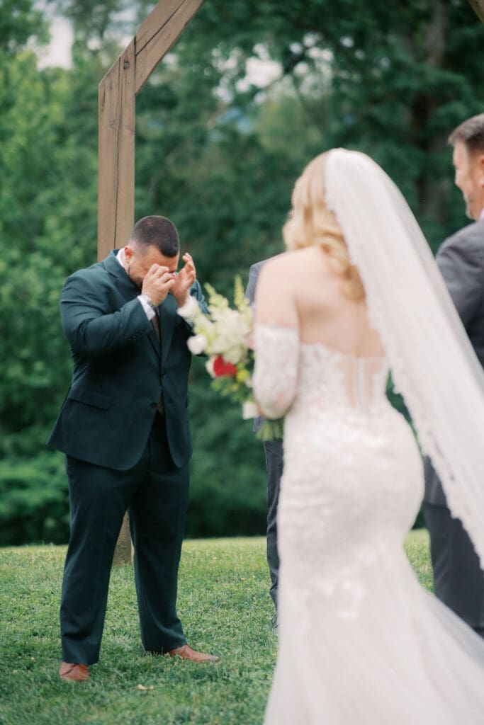 Emotional groom seeing bride for the first time at vineyard ceremony.