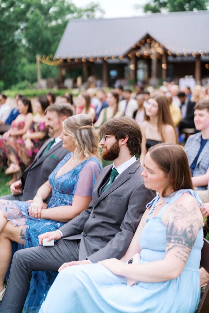 guests sit during ceremony at Harper’s Vineyard wedding in May