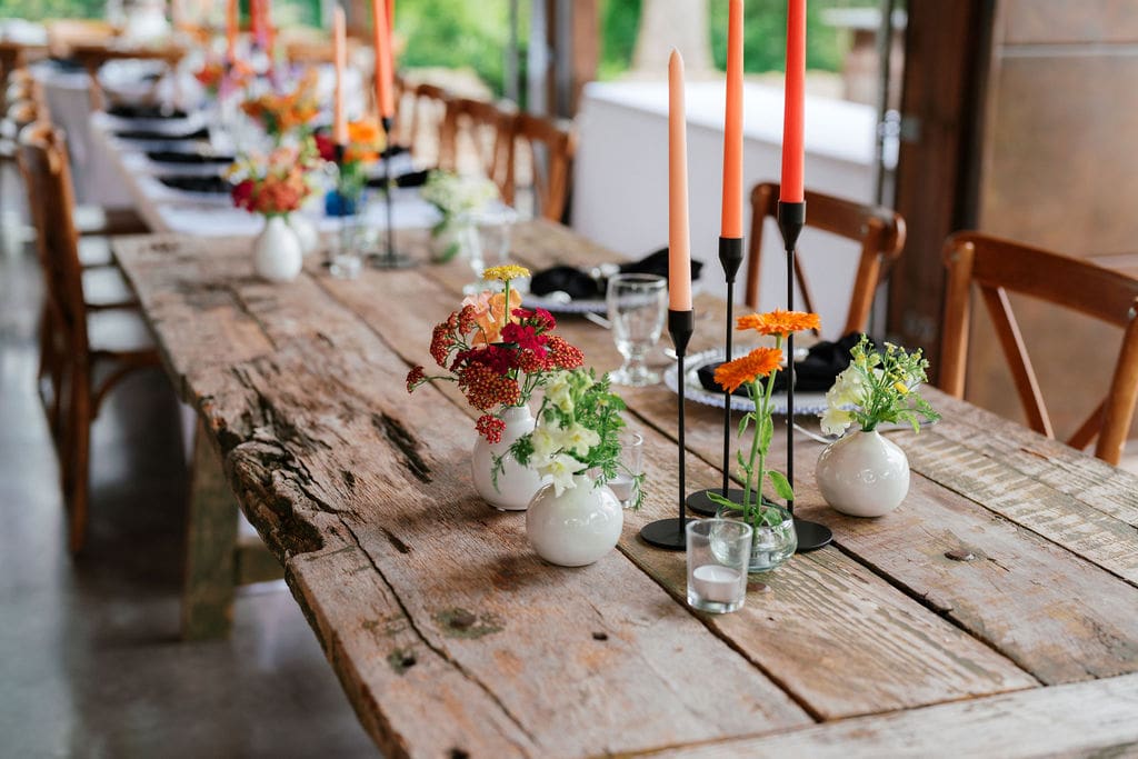Reception table decor with candles, greenery, and rustic wood tables.