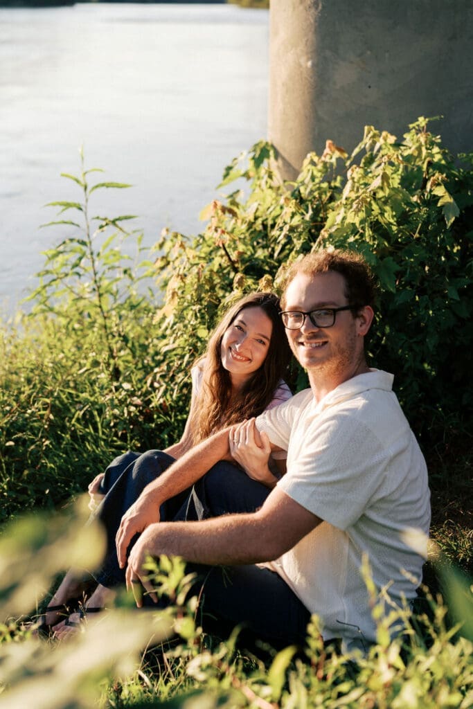 couple sits on the bank of the french broad river at seven islands state birding park in knoxville tennessee