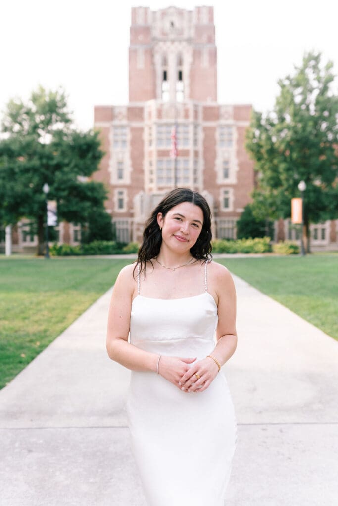 Rachel poses confidently in a white dress on the University of Tennessee Knoxville campus during her senior portrait session.