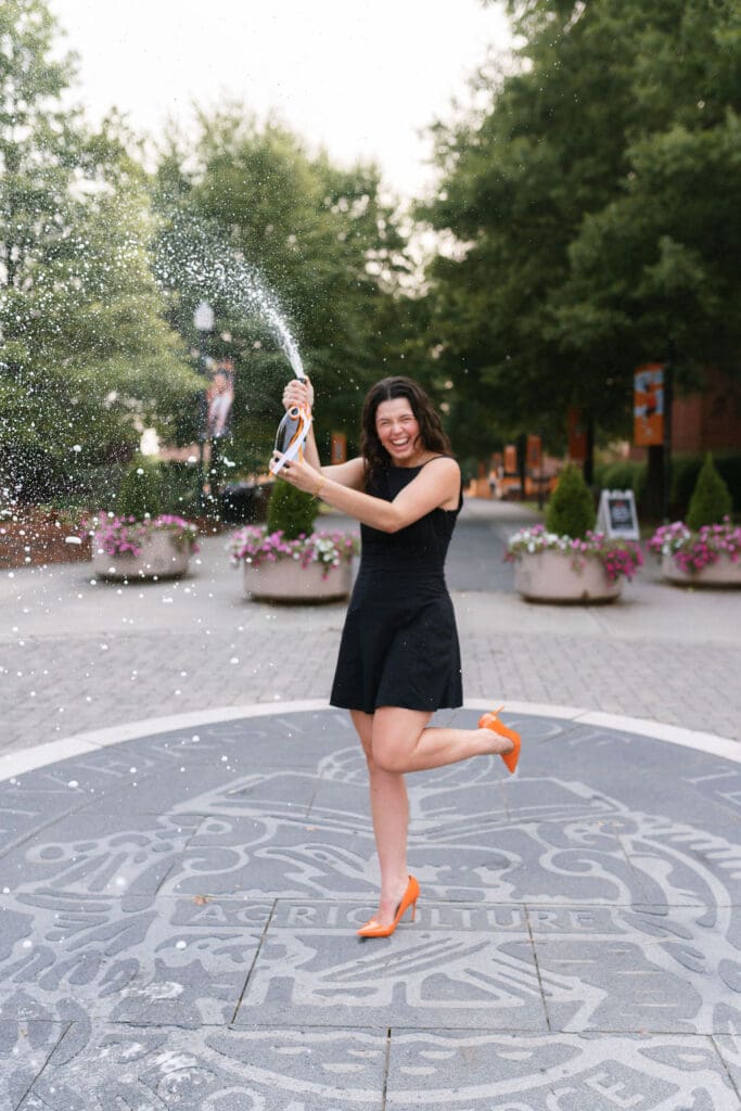 girl in black dress pops champagne on the seal at the university of tennessee knoxville