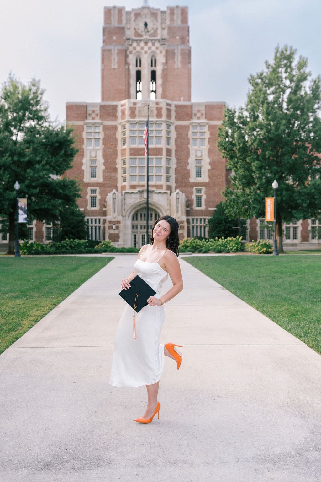 Rachel poses confidently in a white dress on the University of Tennessee Knoxville campus during her senior portrait session.