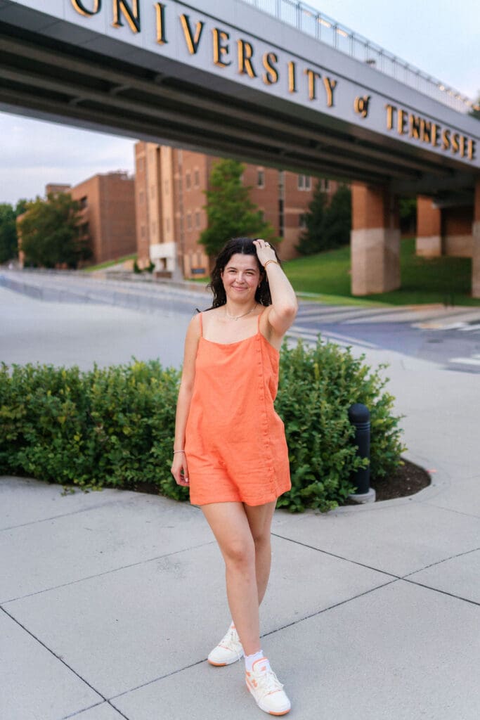 girl in orange dress poses in front of the university of tennessee bridge in knoxville tennessee