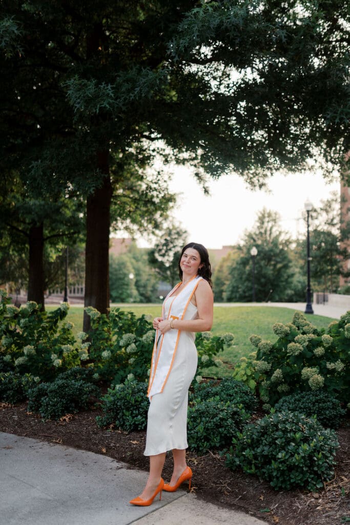 Rachel poses confidently in a white dress on the University of Tennessee Knoxville campus during her senior portrait session.
