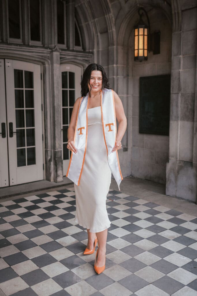 girl in orange heels and white dress poses for senior photos at the university of tennessee knoxville