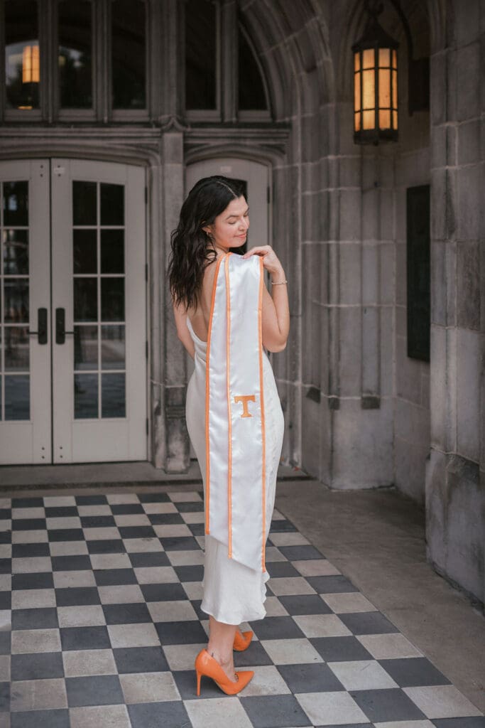 girl in orange heels and white dress poses for senior photos at the university of tennessee knoxville
