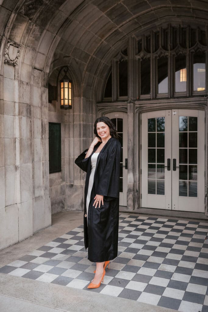 marketing major in cap and gown takes utk senior photos at ayres hall