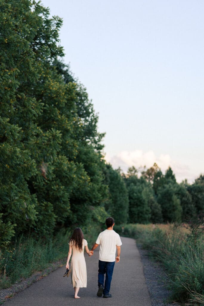 couple holds hands and walks on paved trail at seven islands state birding park in knoxville tennessee