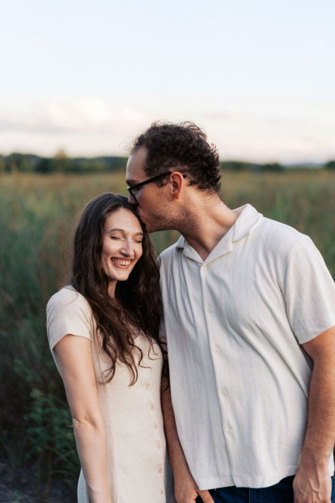 couple kisses in field at seven islands state birding park in knoxville tennessee
