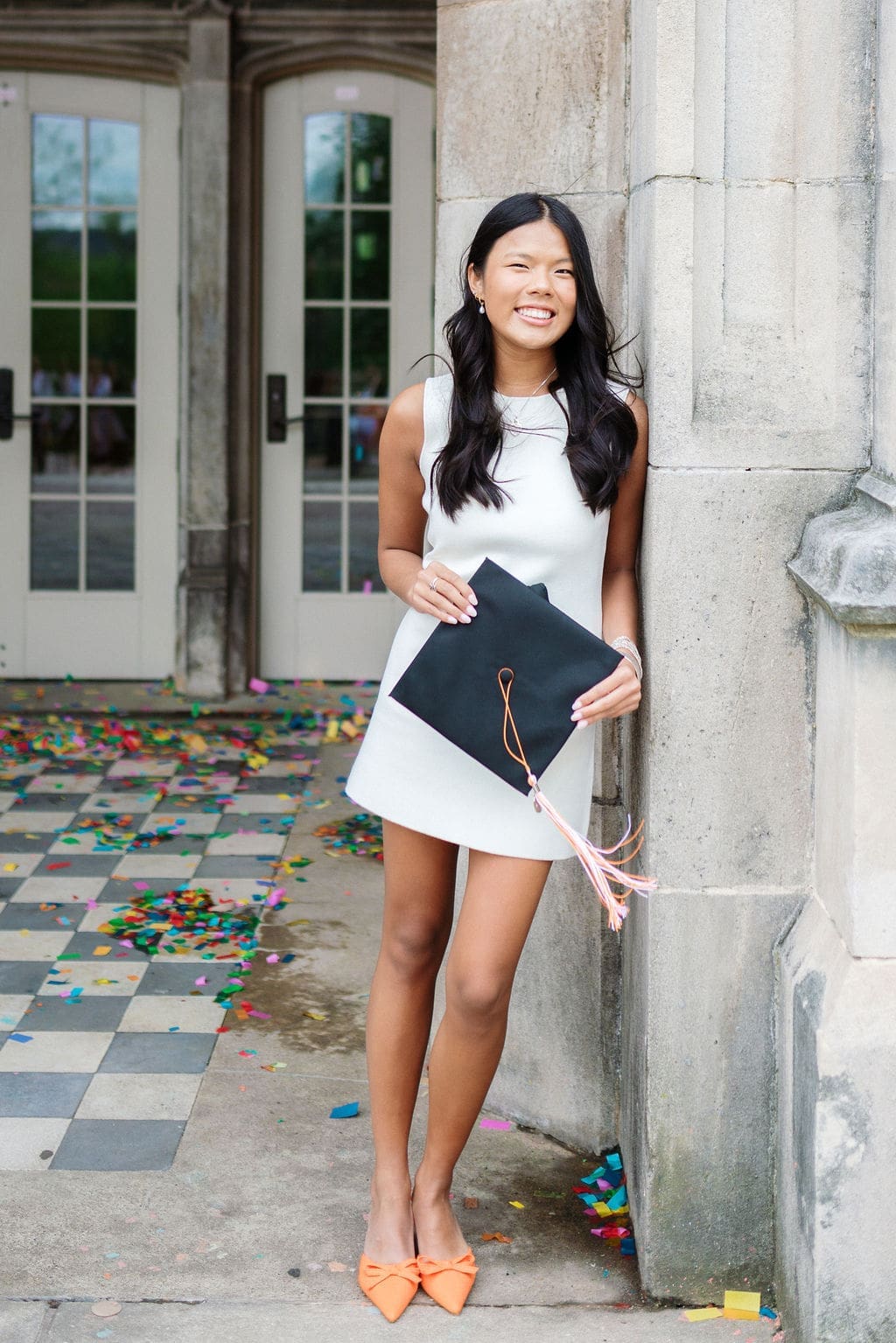 girl in white dress holds graduation cap at Ayres Hall at the University of Tennessee Knoxville for grad photos