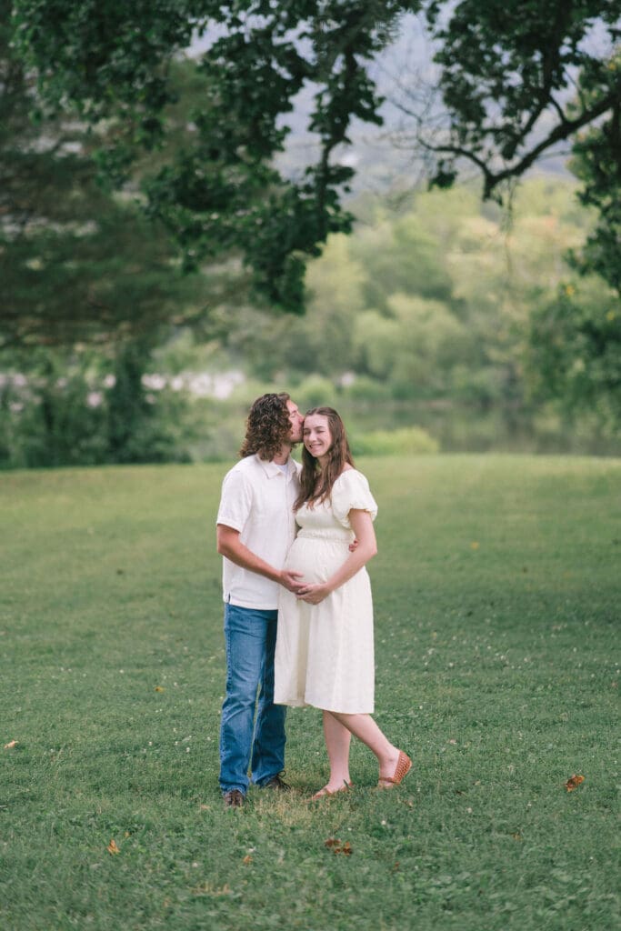Couple kisses in field during maternity photos in Knoxville Tennessee
