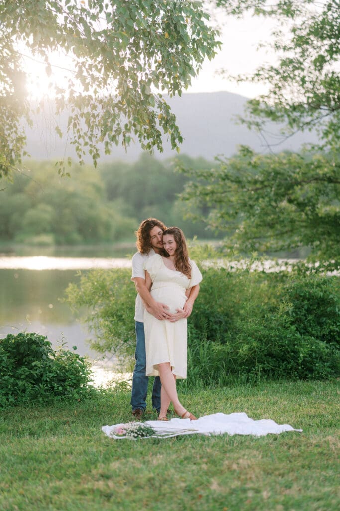 Candid maternity photo of couple embracing during sunset at Cove Lake State Park, captured by Knoxville photographer