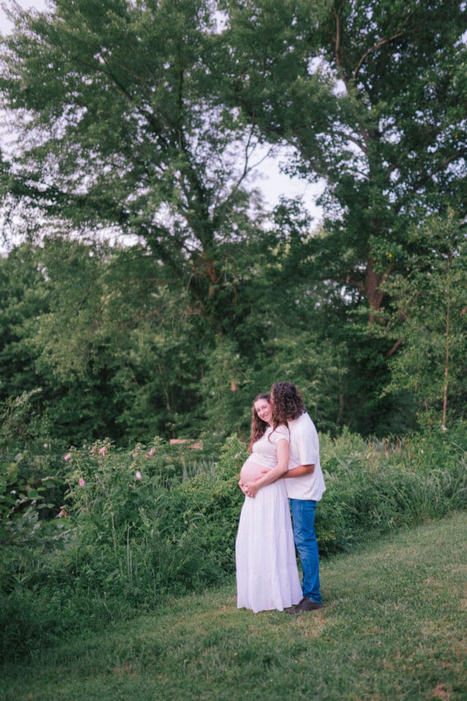 Candid maternity photo of couple embracing during sunset at Cove Lake State Park, captured by Knoxville photographer.