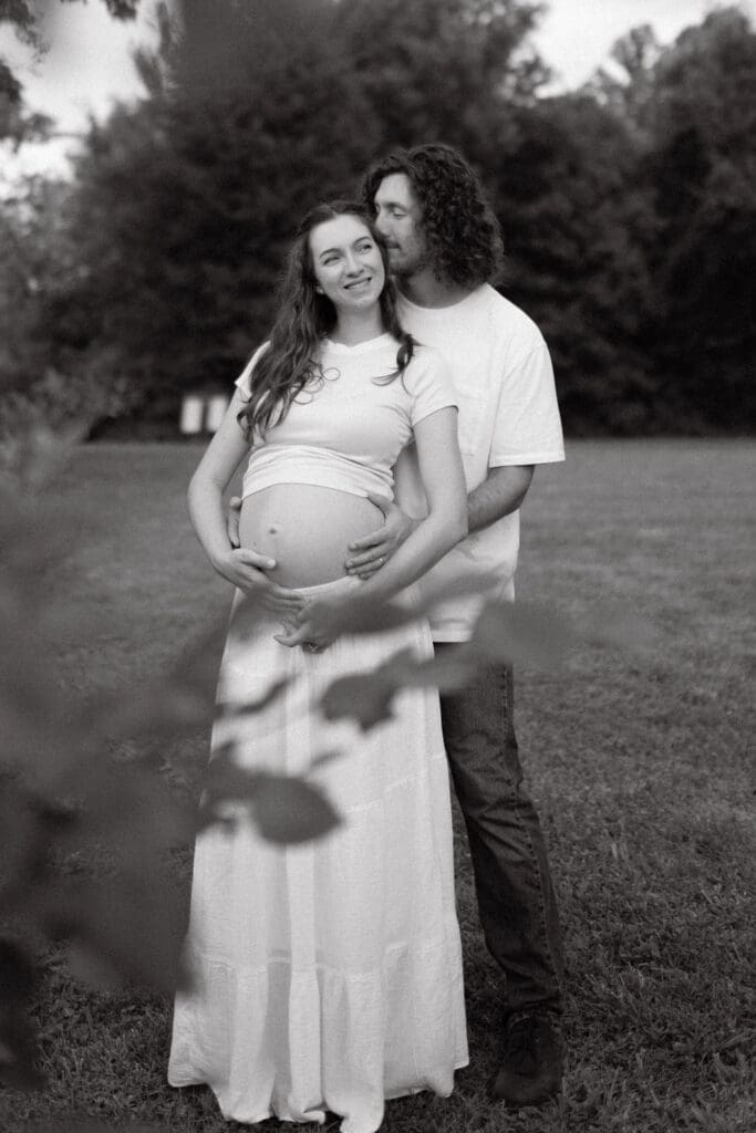 Candid maternity photo of couple embracing during sunset at Cove Lake State Park, captured by Knoxville photographer.