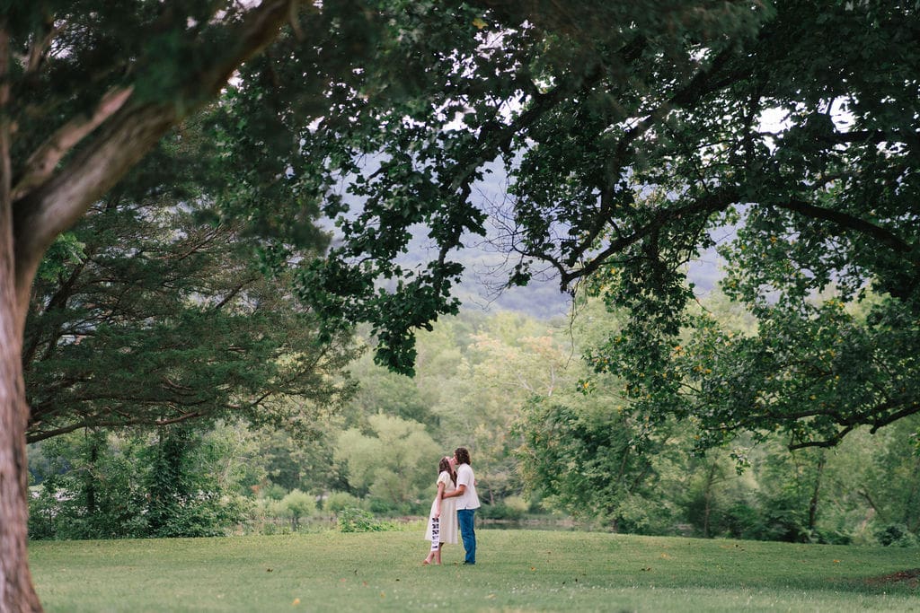 Couple embracing under trees during maternity session at Cove Lake State Park, Tennessee