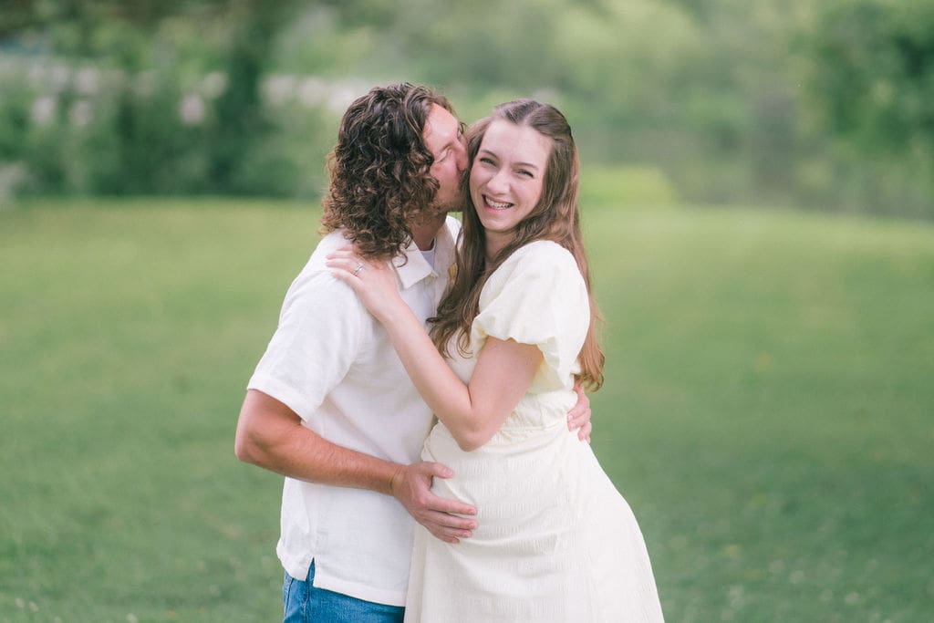 Expecting couple kissing along forest path during maternity session at Cove Lake State Park, Tennessee