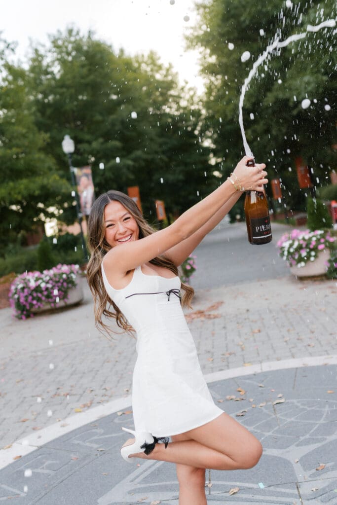 University of Tennessee grad photos of Mindy celebrating graduation popping champagne