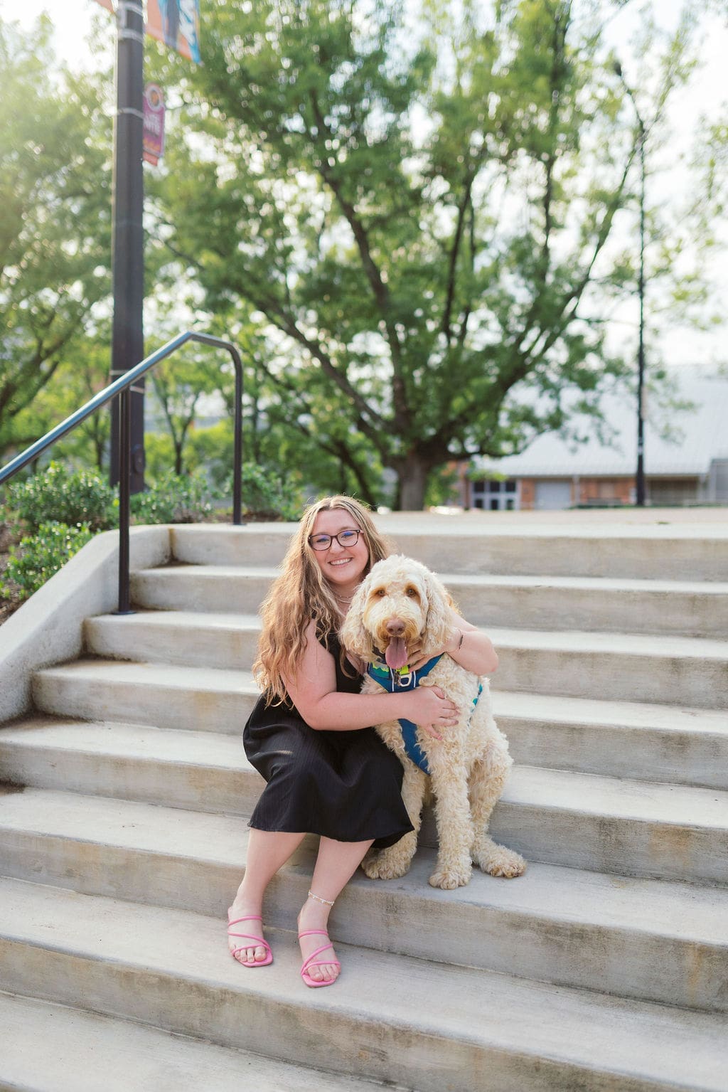 senior smiles with golden doodle dog on the university of tennessee knoxville veterinary campus for graduation photos